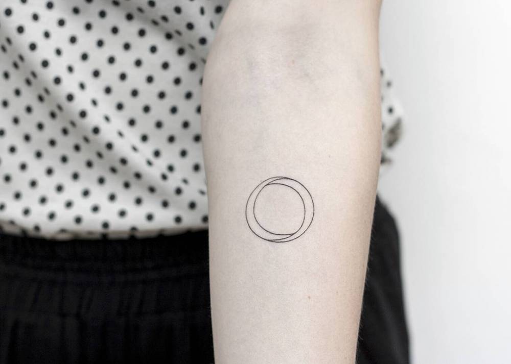 Hand poked minimalist circle tattoo on the left inner forearm.