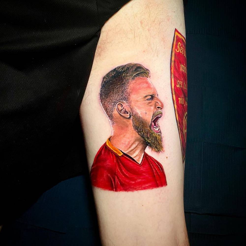 Micro-realistic De Rossi portrait tattoo on the inner arm.