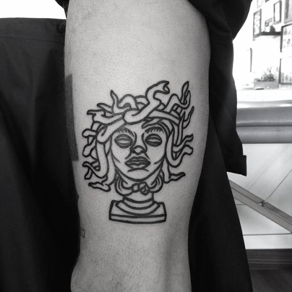 Line art Medusa tattoo on the upper arm.