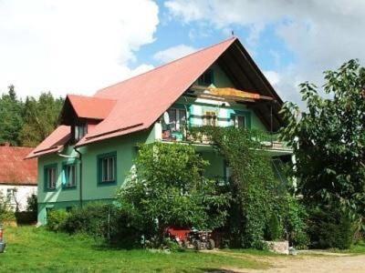 een groen huis met een rood dak bij Agroturystyka Zielone Wzgorze in Sikorzyno