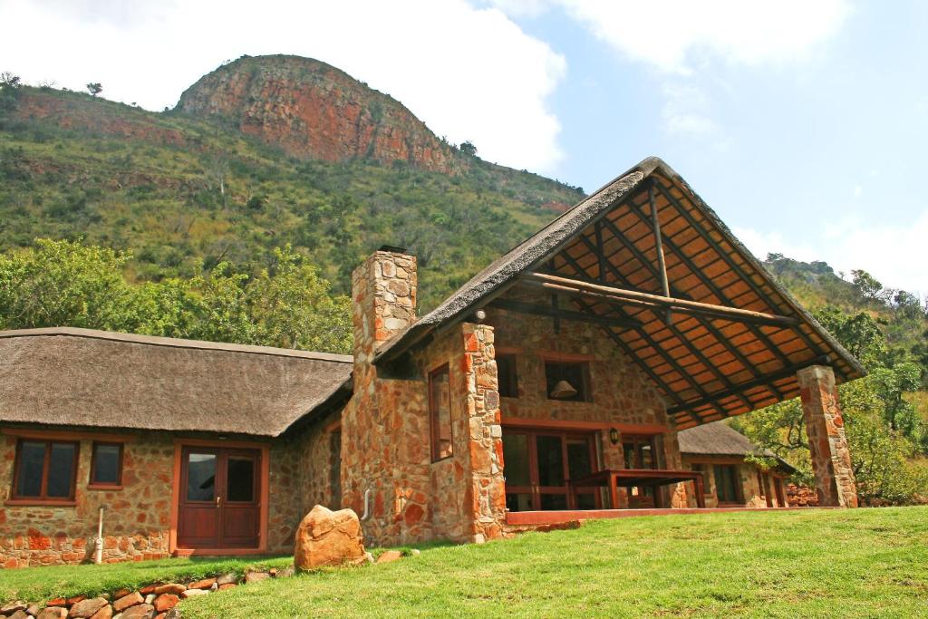 une maison en pierre avec une montagne en arrière-plan dans l'établissement Verlorenkloof, à Dullstroom