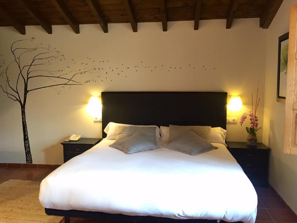 een slaapkamer met een bed en een boom aan de muur bij El Coto Hotel Restaurante in Vitoria-Gasteiz