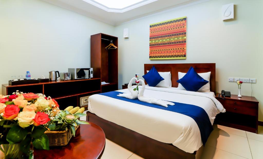 1 dormitorio con 1 cama y 1 mesa con flores en Tanzanite Executive Suites en Dar es Salaam