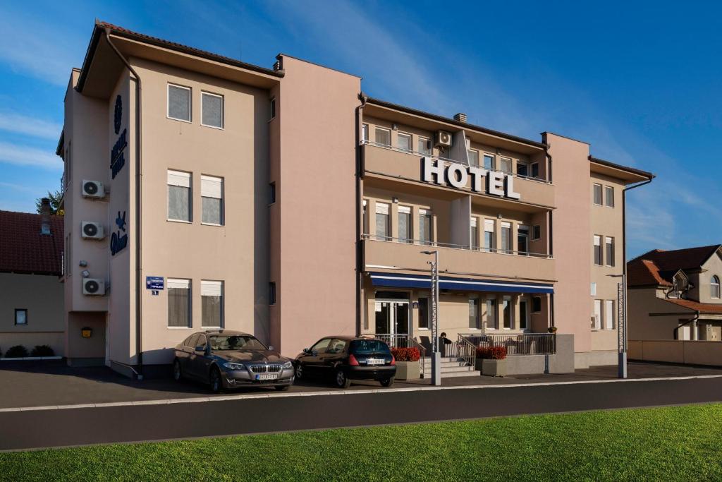 un hotel con dos coches estacionados frente a él en Airport Hotel Garni, en Belgrado