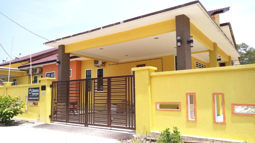 a yellow house with a gate in front of it at Amera Homestay in Cukai