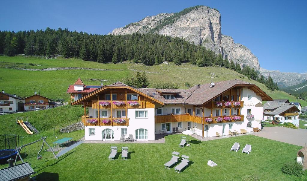 una casa su una collina con una montagna sullo sfondo di Garni La Majon a Selva di Val Gardena