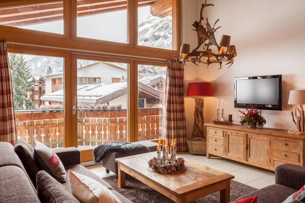 ein Wohnzimmer mit einem Sofa und einem TV in der Unterkunft Vrony Apartments by Hotel Walliserhof Zermatt in Zermatt