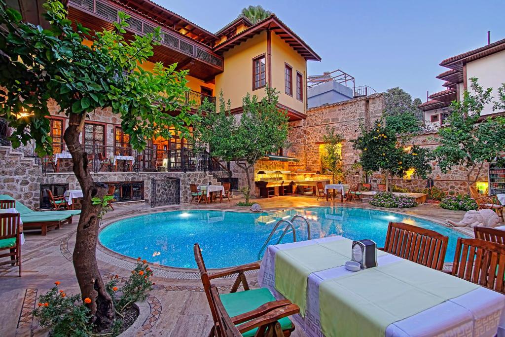 una piscina con mesa y sillas junto a un edificio en La Paloma Hotel, en Antalya