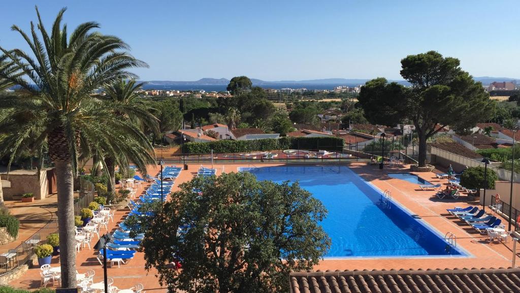 una grande piscina con sedie a sdraio e una palma di Hotel San Carlos a Roses