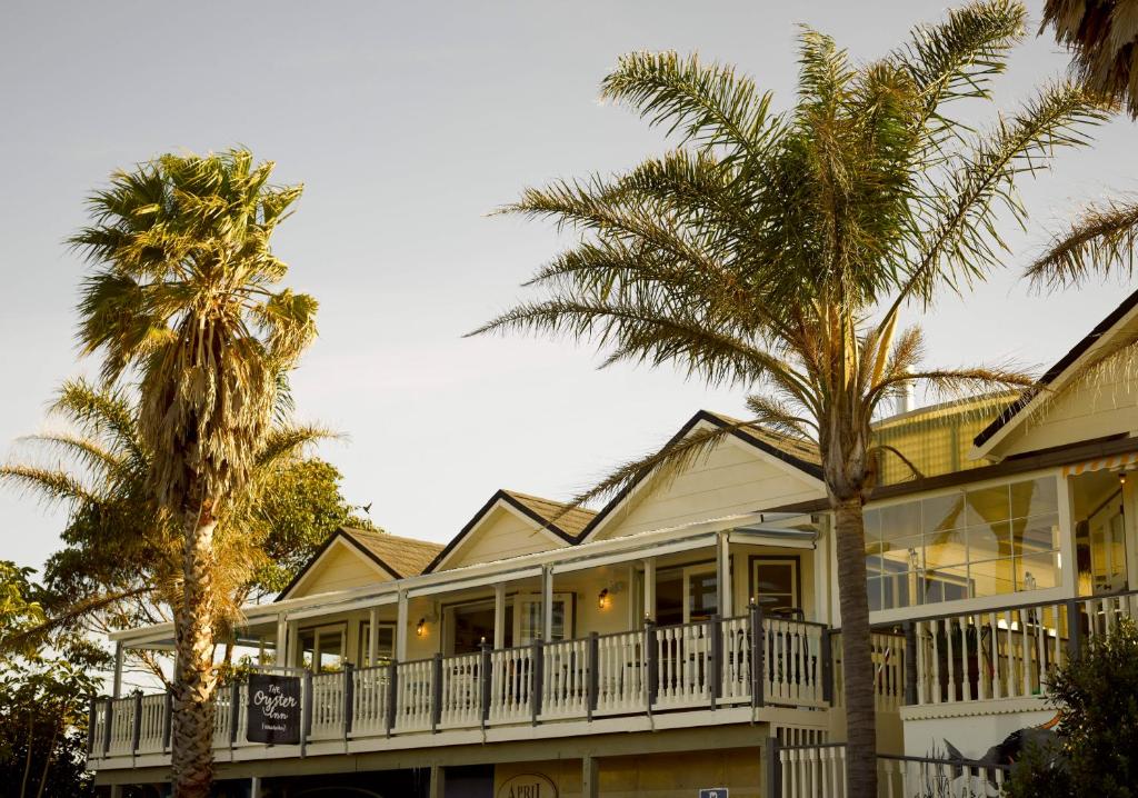 een huis met palmbomen ervoor bij The Oyster Inn in Oneroa