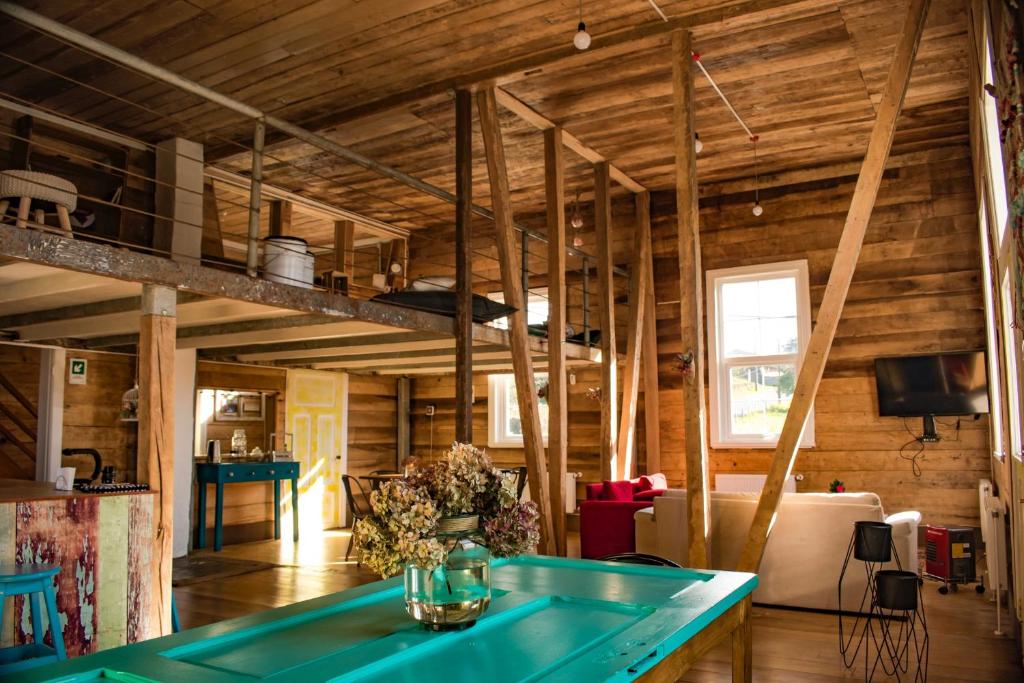 sala de estar con paredes de madera y mesa azul en Casa Apel Hostel en Puerto Varas