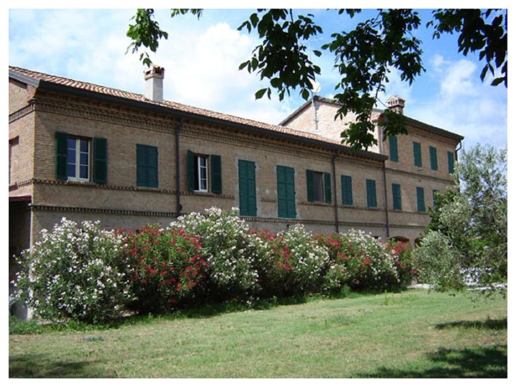 een gebouw met groene luiken en bloemen in een tuin bij Agriturismo Valle Isola "La Tana del Gusto" in Comacchio