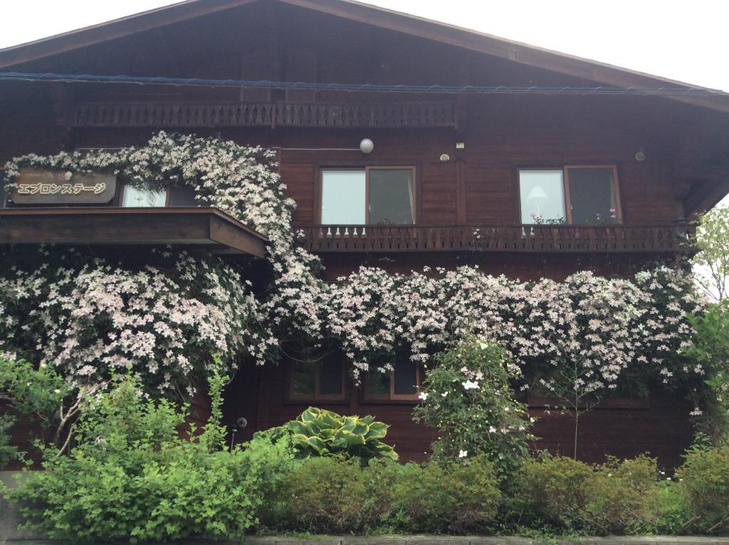 une maison avec des fleurs blanches sur son côté dans l'établissement Yamagata Zao Pension Aplon Stage, à Kaminoyama