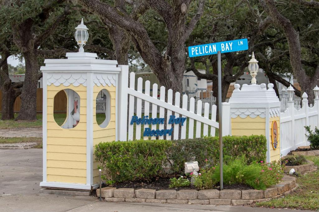 uma cerca branca com uma casa amarela e um sinal de rua em D&R Pelican Bay Resort em Rockport