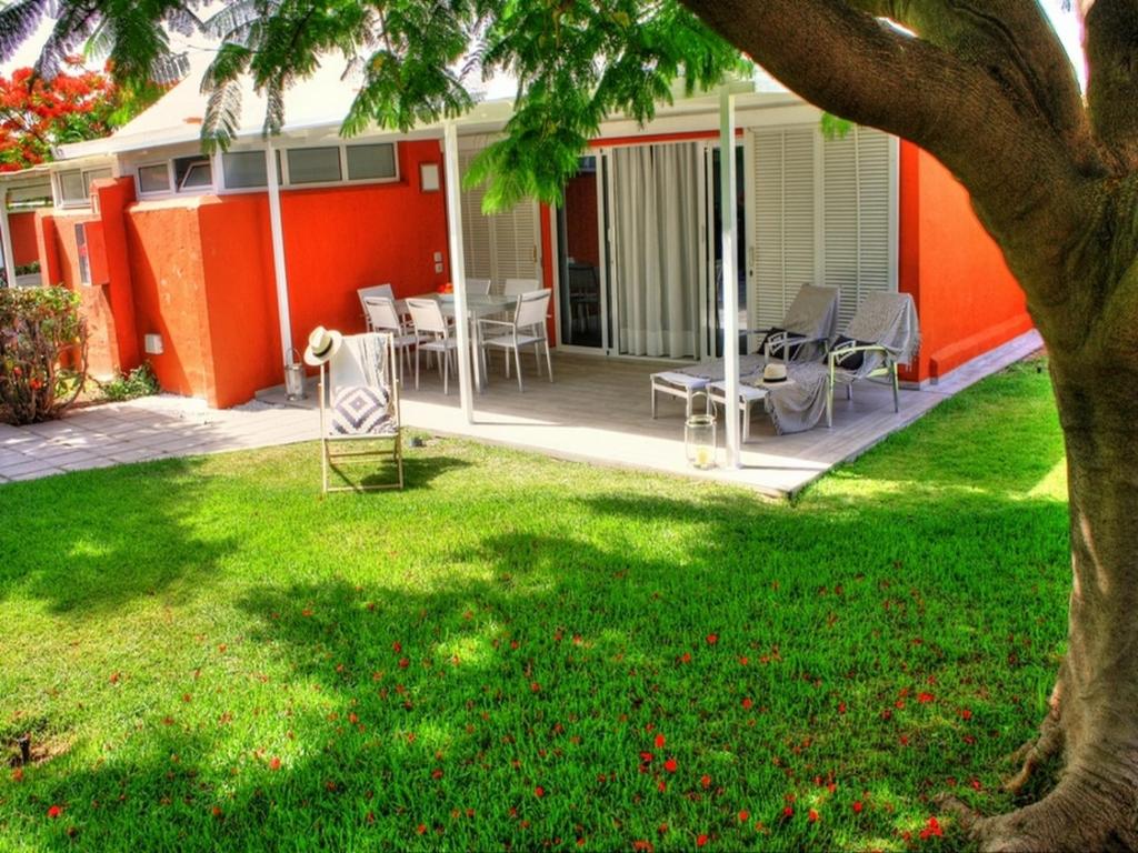 een huis met een tuin met een tafel en stoelen bij Bungalows Los Melocotones in Maspalomas