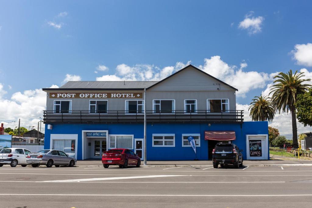 een blauw gebouw met auto's voor het gebouw bij Post Office Hotel in Foxton