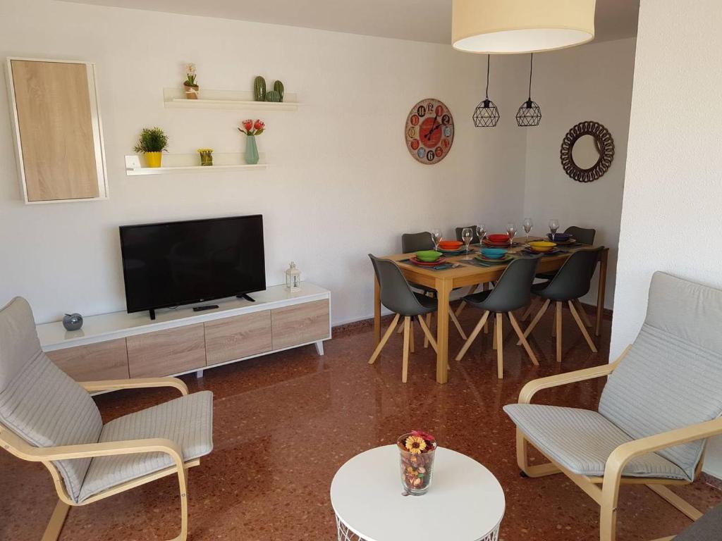 uma sala de estar com televisão e uma mesa com cadeiras em Fantástico apartamento cerca de la playa em Benicàssim