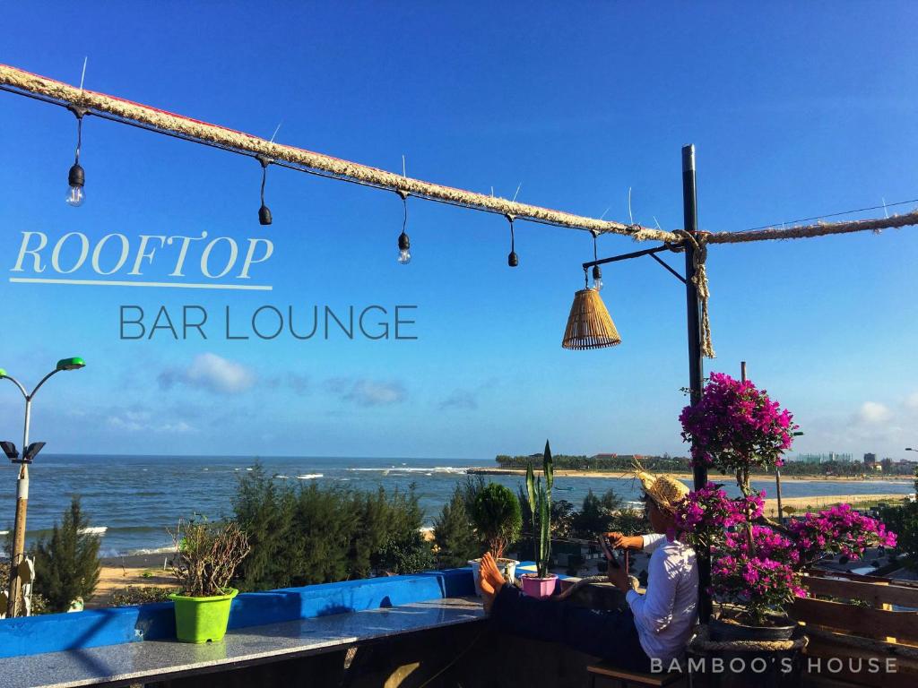 una mujer sentada en un bar con vistas al océano en Bamboo's House, en Dong Hoi