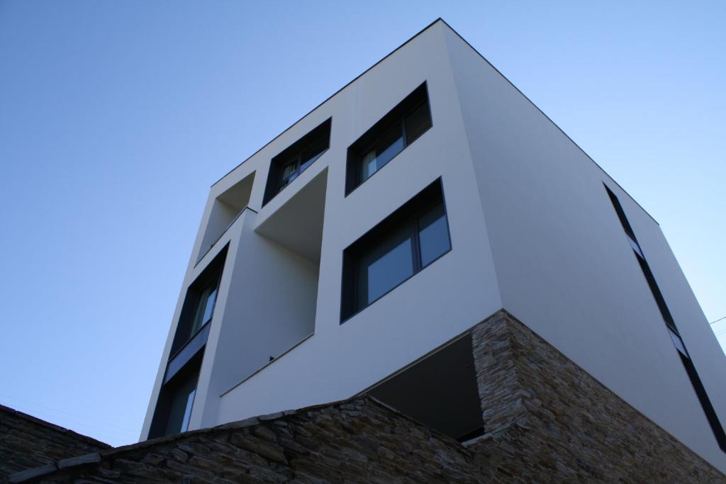 un edificio blanco con ventanas en la parte superior de un edificio de ladrillo en Hostal Tres Campanas, en Villafranca del Bierzo