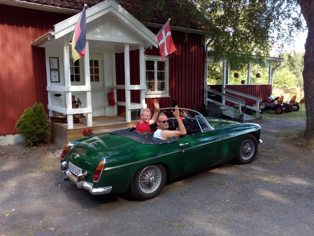 dos niños montados en un coche verde delante de una casa en Torne Camping - Kano & Fiskecamp, en Grimslöv