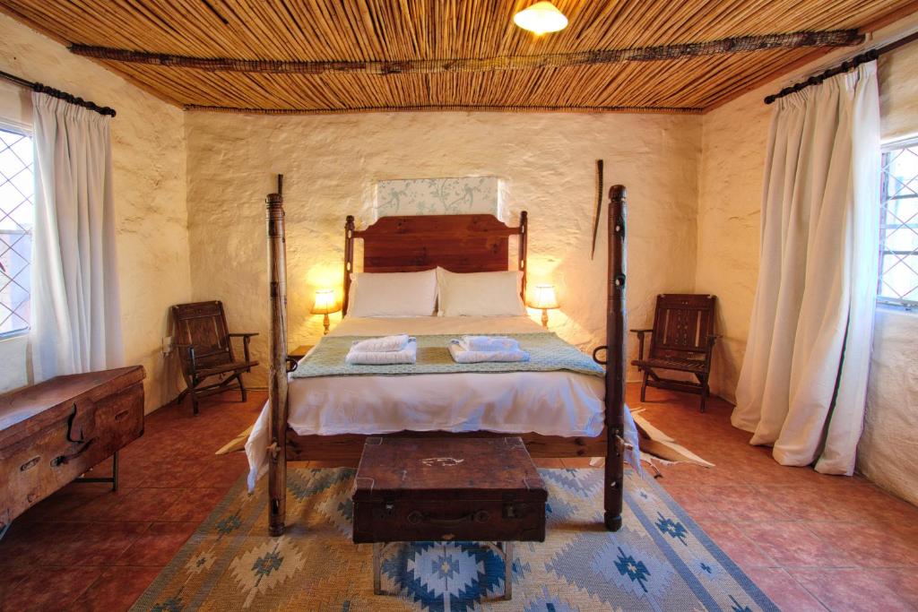 een slaapkamer met een bed in een kamer met ramen bij Ironstone Cottage in Graaff-Reinet