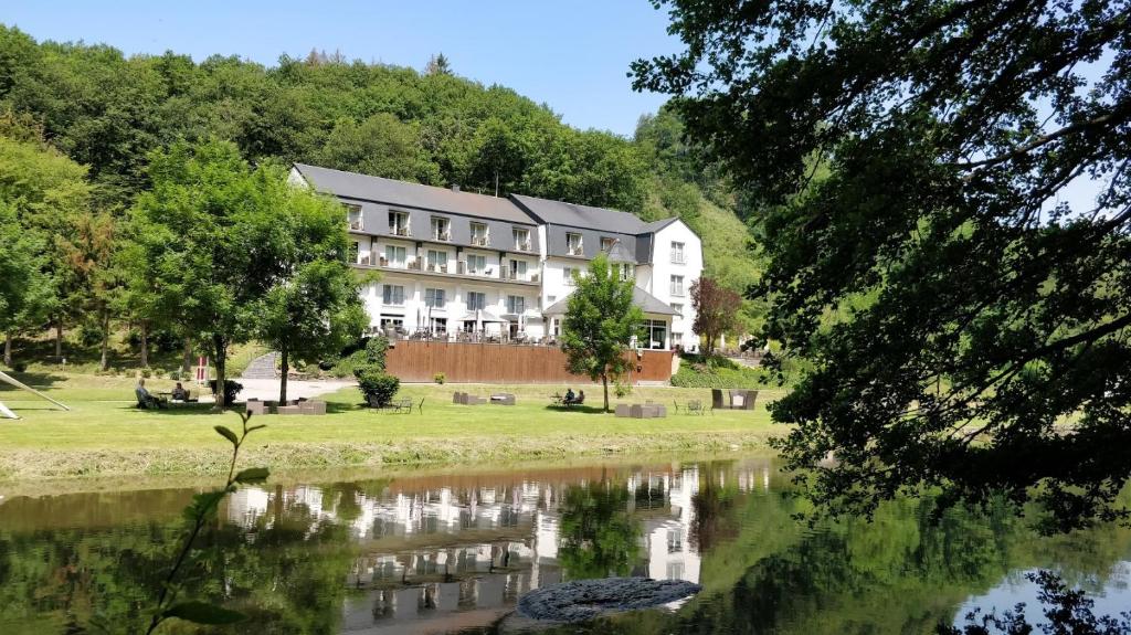 um grande edifício ao lado de uma massa de água em Cocoon Hotel Belair em Bourscheid