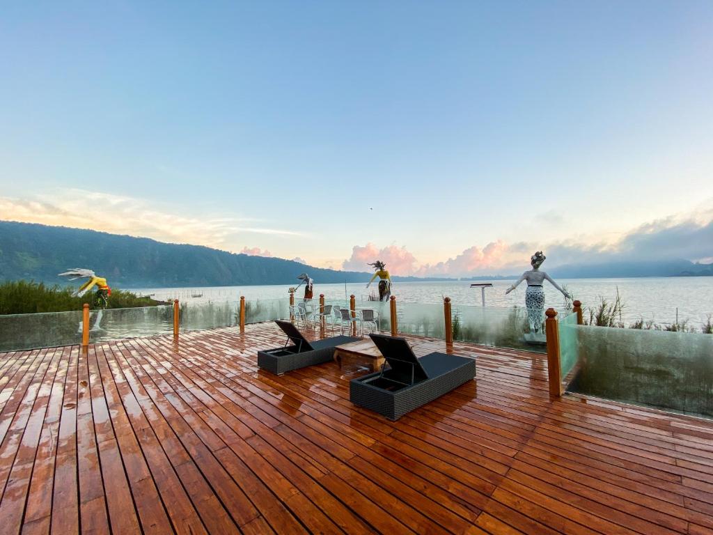 una terrazza in legno con vista su una cassa d'acqua di Pondanu Cabins By The Lake a Bedugul