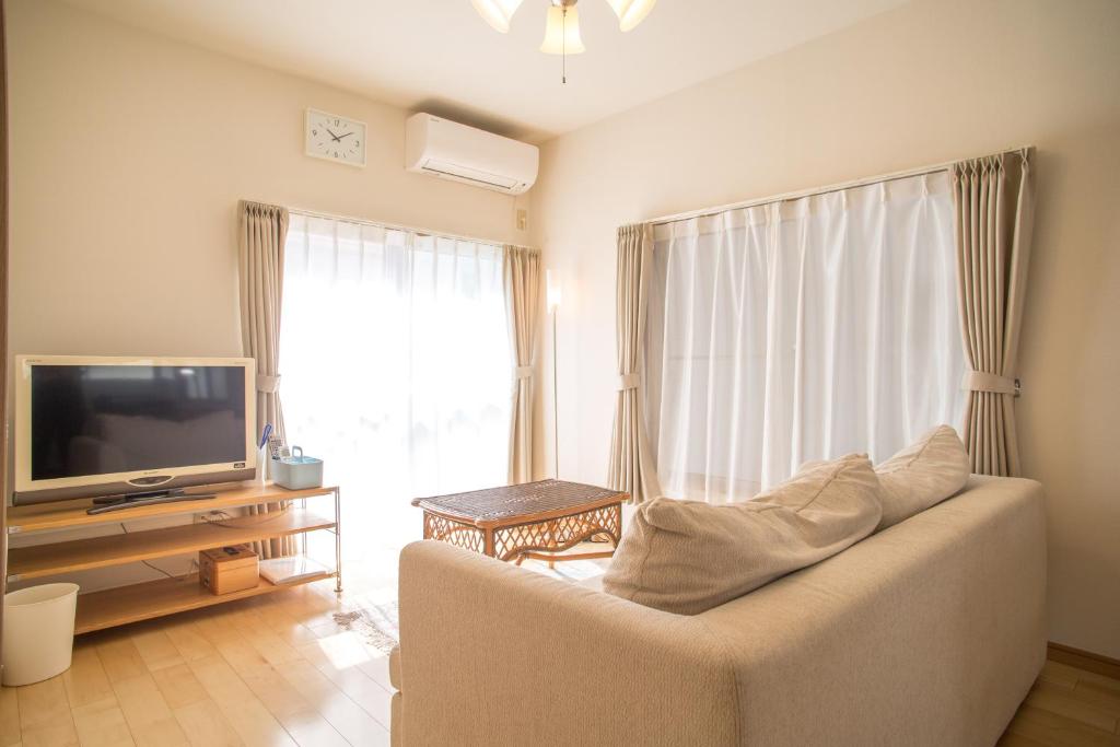 sala de estar con sofá y TV en RIVERSIDE INN KAMAKURA en Kamakura