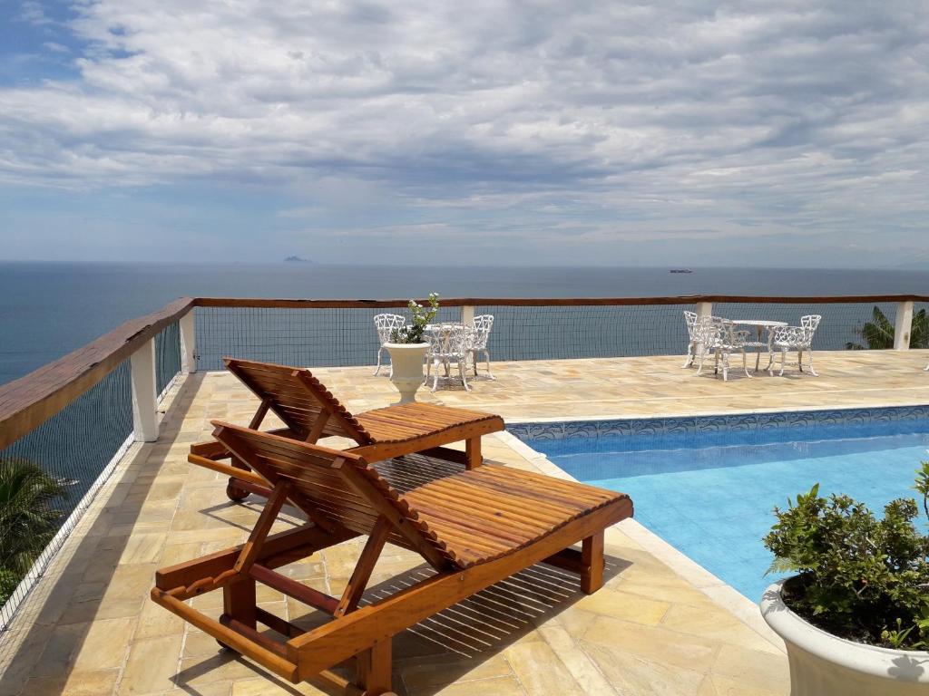 een patio met een tafel en stoelen naast een zwembad bij Casa das Ilhas in Ilhabela