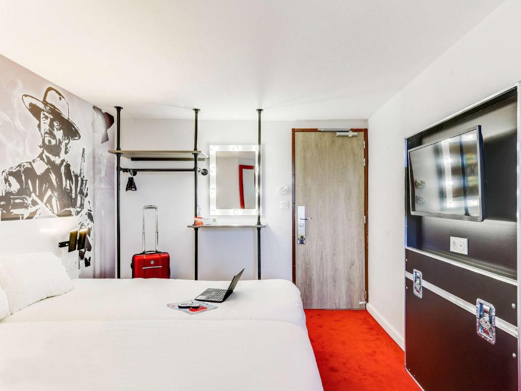 ein Hotelzimmer mit 2 Betten und einem Laptop auf dem Bett in der Unterkunft Ibis Styles Paris Saint Denis La Plaine in Saint-Denis