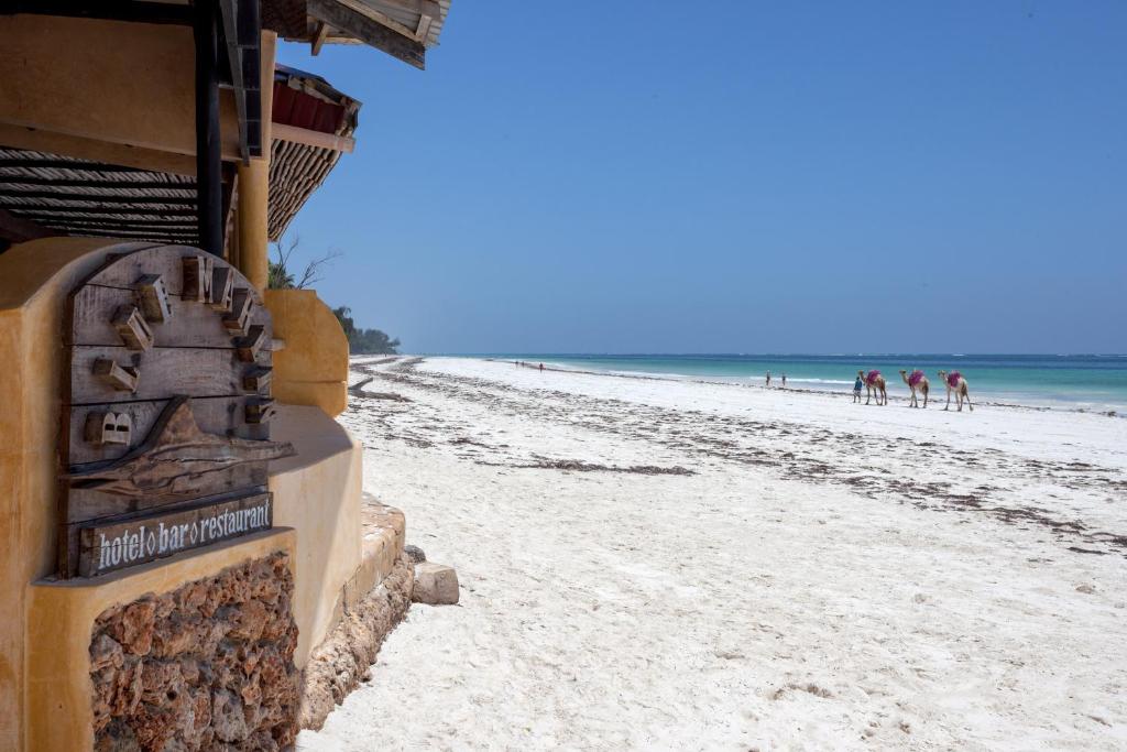 uma praia com um edifício e pessoas na praia em Blue Marlin Beach Hotel em Praia de Diani