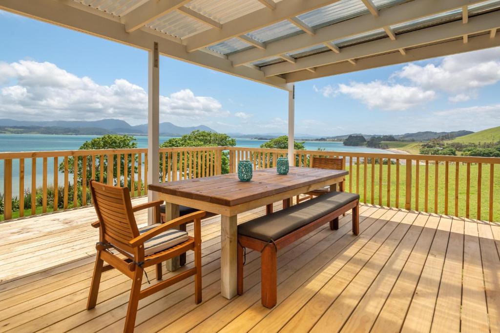 a wooden deck with a wooden table and chairs at ONEPU MOANA 4-6 Bdr Holiday Home in Opononi