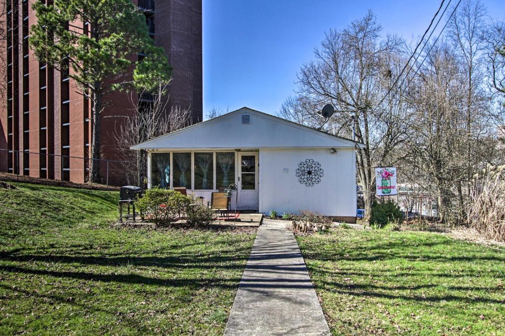 une petite maison blanche sur un trottoir à côté d'un bâtiment dans l'établissement Quaint Getaway 2 Mi to Downtown and 3 Mi to UT!, à Knoxville