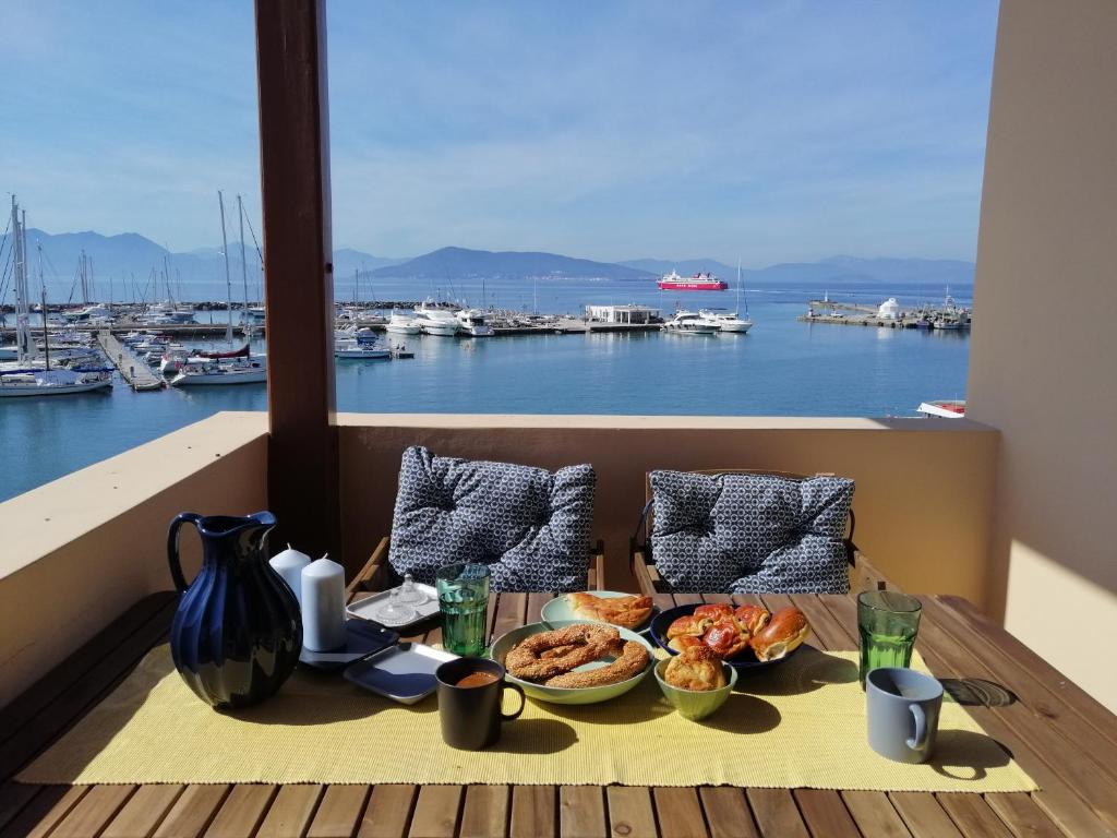 uma mesa com comida numa varanda com vista para um porto em Aegina Port Apt 2-Διαμέρισμα στο λιμάνι της Αίγινας 2 em Aegina Town