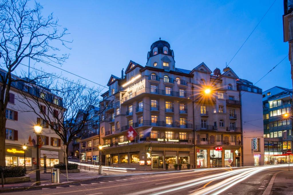 um grande edifício numa rua da cidade à noite em Hotel De la Paix em Lucerna