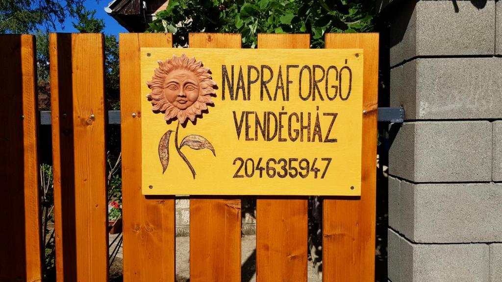 un cartello su una recinzione di legno con un cartello sopra di Napraforgó Vendégház a Gárdony