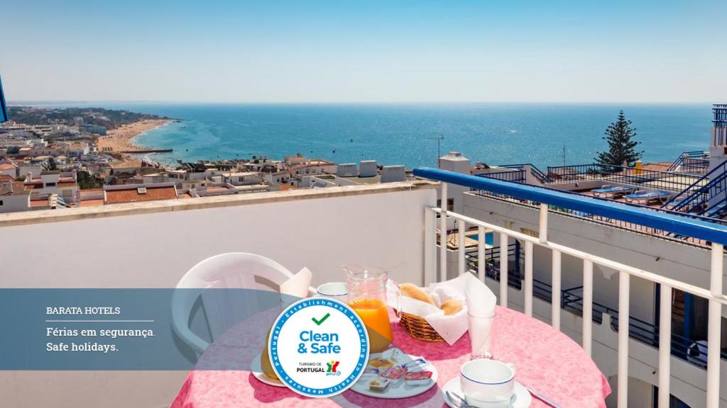 een tafel met eten op een balkon met uitzicht op de oceaan bij Hotel Mar A Vista in Albufeira