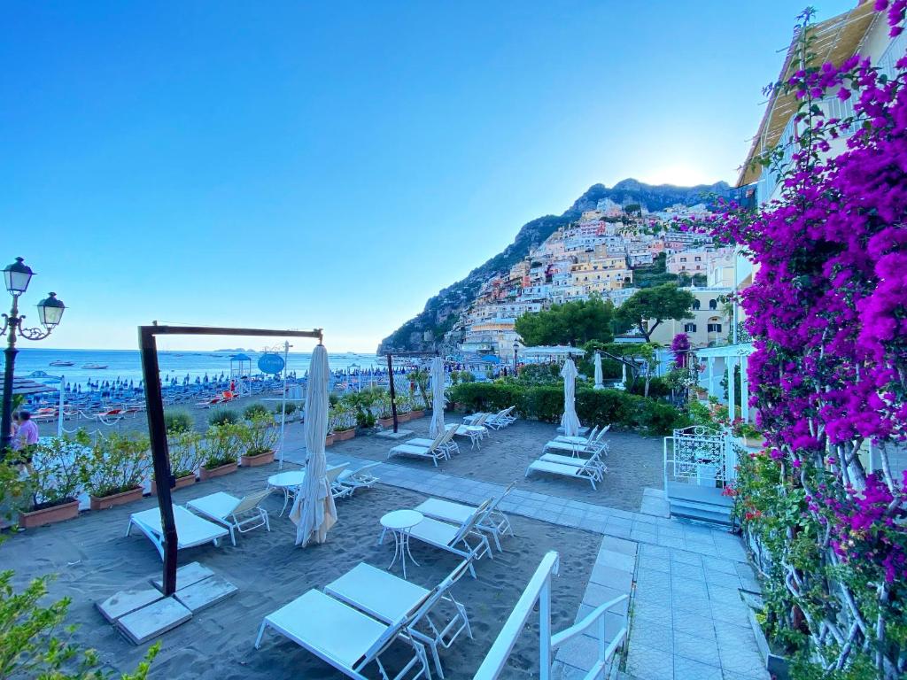 波西塔諾的住宿－La Caravella di Positano - Relais & Beach，海滩上的一组椅子和遮阳伞