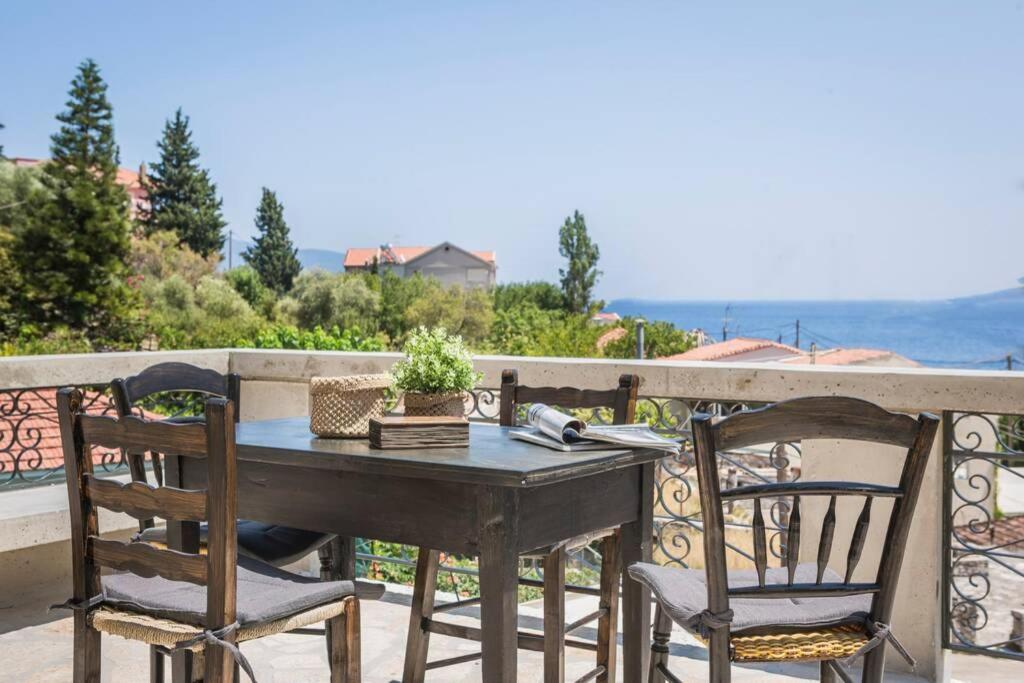 un tavolo e sedie su un balcone con vista sull'oceano di la casa di zia Anna Agia Efimia village a Ayia Evfimia