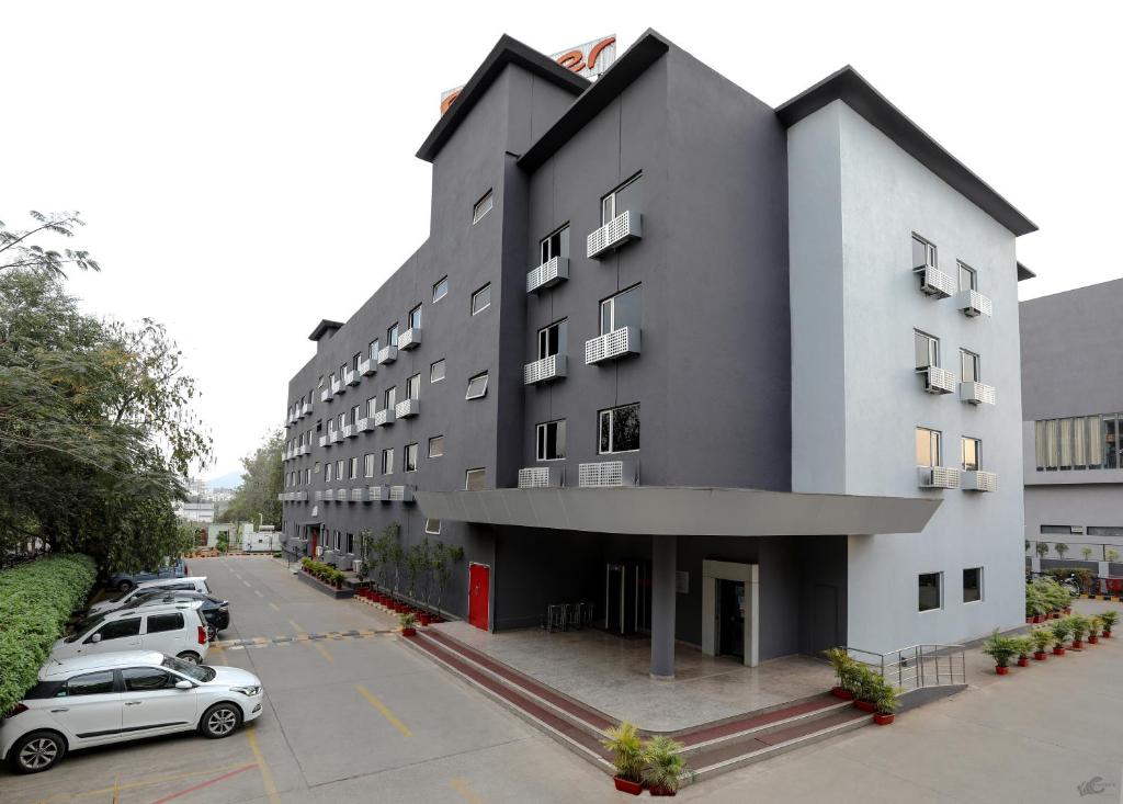 a large gray building with cars parked in a parking lot at Ginger Nashik in Nashik