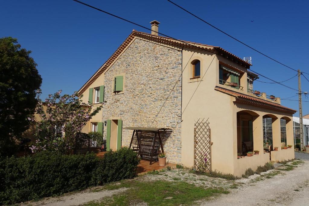 Casa de piedra pequeña con puertas verdes y ventana en Gîte du Pagoulin - Chambres d'hôtes, en Hyères