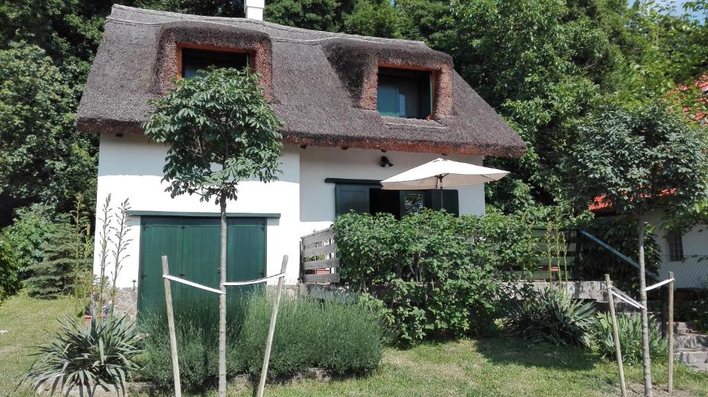 ein Haus mit einem Strohdach und einer grünen Tür in der Unterkunft Peace & Beach House in Tihany, Sajkod in Tihany