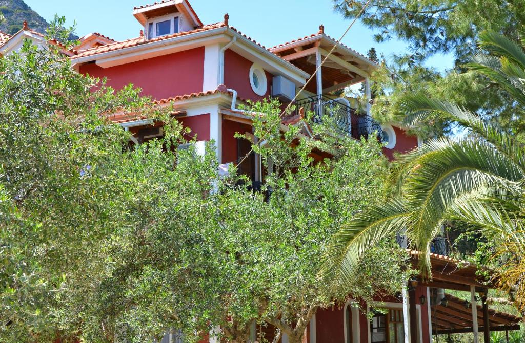 uma casa vermelha com árvores em frente em Belvedere Zakynthos Studios em Vasilikos