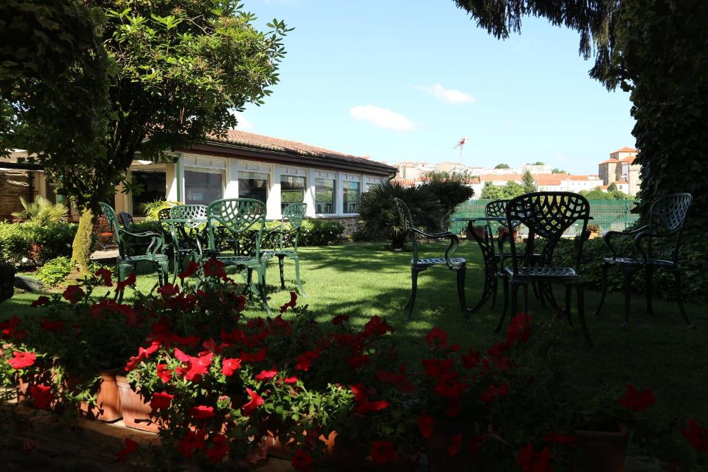 een groep stoelen en bloemen in een tuin bij Hotel Virxe da Cerca by Pousadas de Compostela in Santiago de Compostela