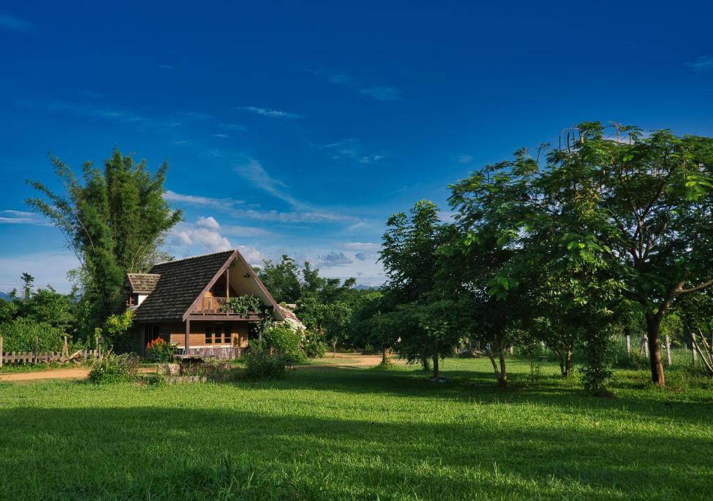 una casa in mezzo a un campo con alberi di Cozycomo Chiang Dao - Wiang Mek a Chiang Dao