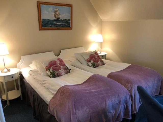 - une chambre avec 2 lits avec des fleurs roses dans l'établissement Hotell Turistgården i Simrishamn, à Simrishamn