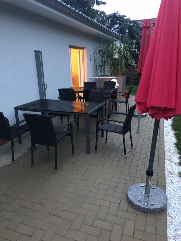 un patio con mesa, sillas y sombrilla rosa en Schilfblume en Großkoschen