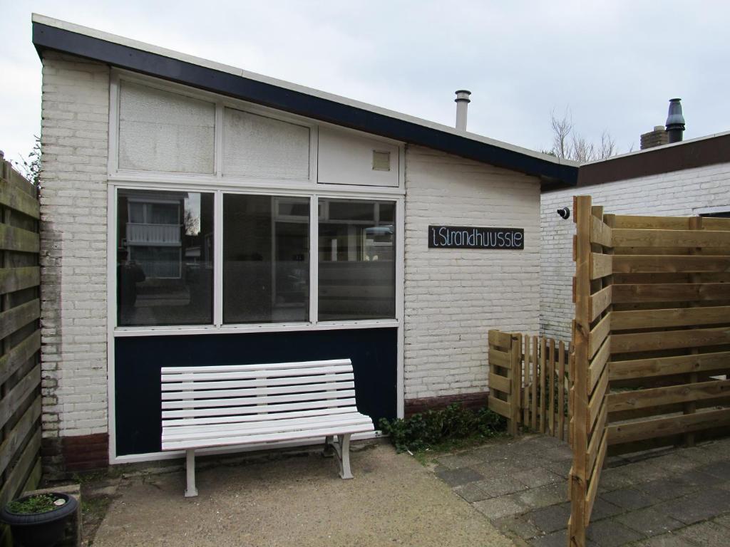 ein weißes Gebäude mit einer Bank davor in der Unterkunft Strandhuussie Texel in De Koog