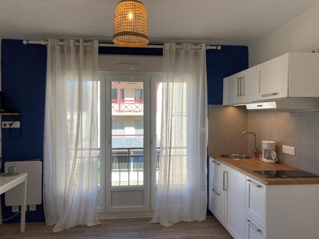 cocina con cortinas blancas y puerta con ventana en La Capitane en La Baule