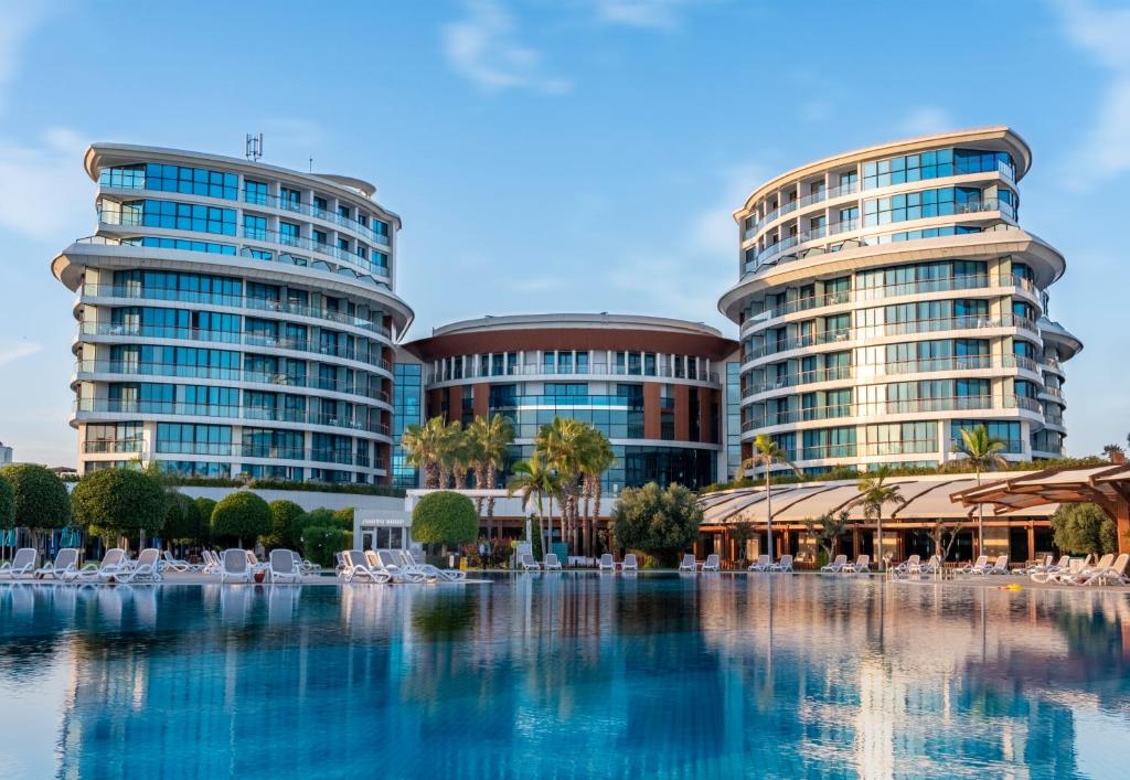 zwei hohe Gebäude mit Stühlen vor einem Pool in der Unterkunft Baia Lara Hotel in Lara